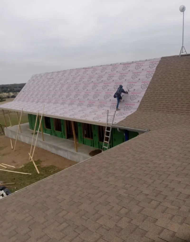 Worker preparing underlayment for a metal roof installation in Picayune